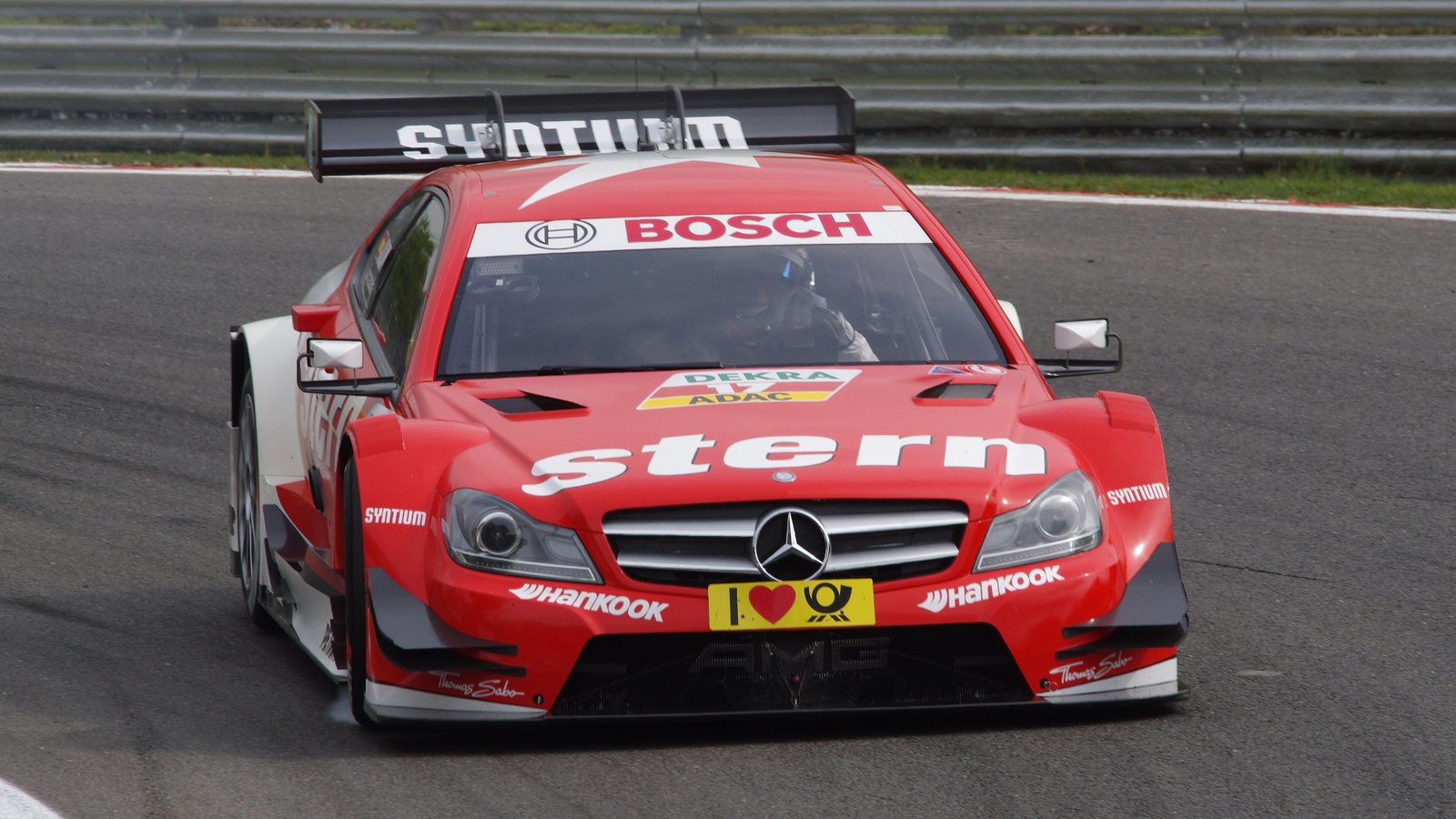Mercedes de carreras rojo y blanco del DTM tomando una curva en Brands Hatch